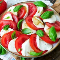 Frischer Tomate Mozzarella Salat mit Basilikum, beträufelt mit Olivenöl.