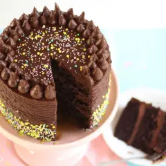 Eine köstliche Schokocreme Torte mit bunten Streuseln und Schokostückchen. Ein Stück ist bereits angeschnitten.