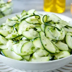 Frischer Salat aus dünn geschnittenen Zucchinischeiben, mariniert mit Kräutern und Öl. Perfekt, um Zucchini roh zu essen.