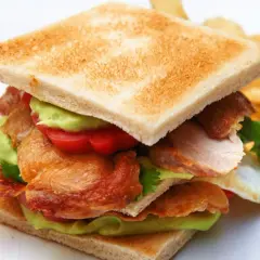 Ein saftiges Club Sandwich Rezept mit Hähnchen, Avocado, Tomaten und knusprigem Speck. Dazu Kartoffelchips.