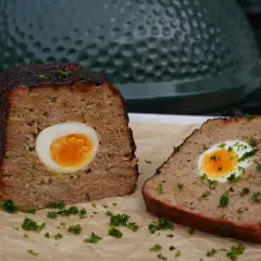 Ein saftiger falscher Hase, aufgeschnitten und mit einem gekochten Ei im Inneren, garniert mit Petersilie.