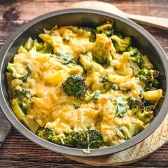 Ein goldbraun überbackener Kartoffel Brokkoli Auflauf mit geschmolzenem Käse und frischer Petersilie, bereit zum Servieren.