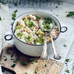 Ein cremiger Reis-Salat mit Hähnchen, Mais und Tomaten, garniert mit Frühlingszwiebeln und Petersilie. Perfekt für ein leichtes Mittagessen.