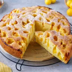 Ein goldbrauner mirabellen kuchen, mit Puderzucker bestäubt, wartet auf seine Genießer. Ein Stück ist bereits herausgeschnitten.