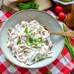 Schmackhaftes Fleischsalat Rezept, garniert mit frischen Kräutern. Dazu Radieschen, Salz und ein Pfeffermühlen-Set.