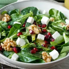 Feldsalat-Rezept: Grüner Salat mit Granatapfelkernen, Walnüssen und Feta-Würfeln, beträufelt mit einem leichten Dressing.