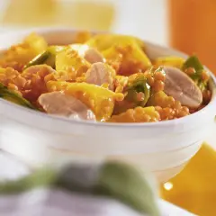Schüssel mit einem leckeren roten Linsen Rezept, garniert mit gelben Paprikastücken und Fleischstreifen.