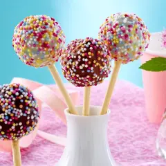 Bunte cake pops mit Schokoglasur und Streuseln in einer weißen Vase, bereit für eine fröhliche Feier.