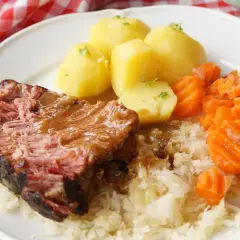 Saftiger Kassler im Ofen mit Salzkartoffeln, Möhren und Sauerkraut. Ein deftiges Gericht, das auf der Zunge zergeht.