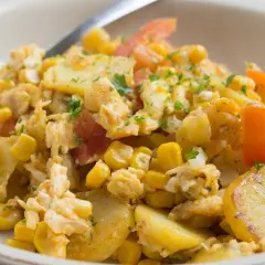 Herzhaftes Gericht mit Kartoffelscheiben, Rührei, Mais und Tomaten. Ein leckeres Beispiel für Kartoffel Gerichte.
