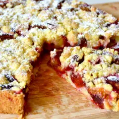 Saftiger Zwetschgenkuchen mit Hefeteig und Streuseln, frisch aus der Springform, mit Puderzucker bestäubt.