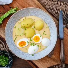 Klassische eier rezepte: gekochte Eier mit Kartoffeln und einer cremigen Sauce, garniert mit Schnittlauch.