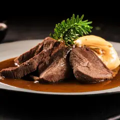 Zartes Tafelspitz-Rezept auf einem Teller mit Sauce, Beilage und Rosmarinzweig.