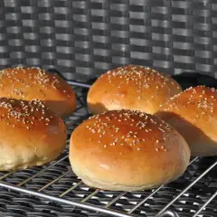 Fünf goldbraune Burgerbrötchen mit Sesam, frisch gebacken nach einem tollen burger buns rezept.