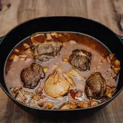 Herzhafte schmorgerichte im gusseisentopf, mit zarten Fleischröllchen und aromatischem Gemüse, köcheln in einer tiefen, dunklen Sauce.