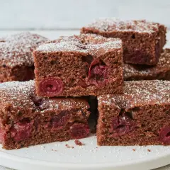 Saftiger Schokokuchen vom Blech mit Kirschen, bestäubt mit Puderzucker. Ein Genuss für jeden Schokoladenliebhaber.