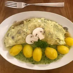 Ein Omelett mit Pilzen, serviert mit kleinen Kartoffeln und grüner Sauce. Perfekt für Pilz-Rezepte!