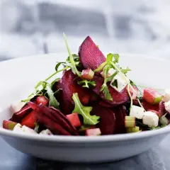Ein köstlicher rote beete salat mit Rucola, Feta und Apfelstücken in einer weißen Schüssel.