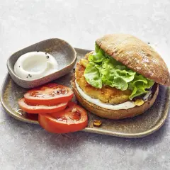 Ein saftiger vegetarischer Burger mit knackigem Salat, dazu frische Tomatenscheiben und eine cremige Sauce. Ein Genuss für alle Sinne!