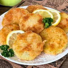Knusprige Kohlrabi-Schnitzel auf einem Teller mit Zitronenscheiben und Petersilie garniert. Ein köstliches vegetarisches Gericht.