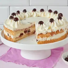 Saftiger Kuchen mit Sahne und Kirschen, perfekt zum Amarenakirschen selber machen. Ein Stück fehlt, daneben eine Schale mit Kirschen.