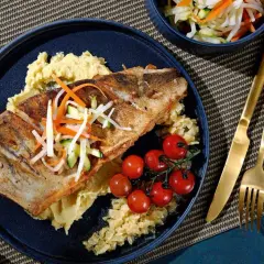 Gebratener Fisch auf Kartoffelpüree mit Kirschtomaten und knackigem Gemüse. Eine köstliche Beilage, die gut zu Kabeljau passt.