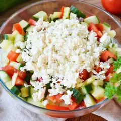 Frischer Schopska Salat mit Gurken, Tomaten und viel zerbröseltem Schafskäse, garniert mit Petersilie.