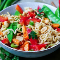 Bunter mie nudel salat mit Erdnüssen, Paprika, Zuckerschoten und Karotten, garniert mit Petersilie.
