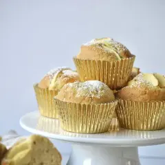 Goldene Apfelmuffins, bestäubt mit Puderzucker, warten auf das apfelmuffins rezept.