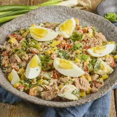 Herzhafter Thunfischsalat mit Mais, Tomaten, Ei und Frühlingszwiebeln, garniert mit hartgekochten Eierspalten.