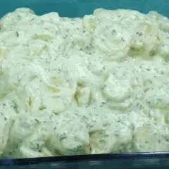 Cremiger Kartoffelsalat mit Kräutern und einem Hauch Balsamico, serviert in einer Glasform.