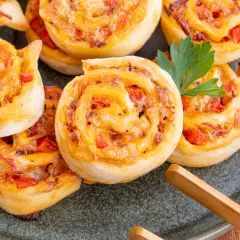 Goldbraune Pizzaschnecken mit Tomaten und Käse, garniert mit Petersilie. Ein leckeres Pizzaschnecken Rezept für jeden Anlass.