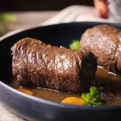 Zwei saftige Rouladen im Schnellkochtopf, serviert mit Karottenstücken und Petersilie in einer dunklen Sauce.