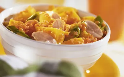 Schüssel mit einem leckeren roten Linsen Rezept, garniert mit gelben Paprikastücken und Fleischstreifen.