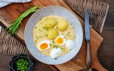 Klassische eier rezepte: gekochte Eier mit Kartoffeln und einer cremigen Sauce, garniert mit Schnittlauch.