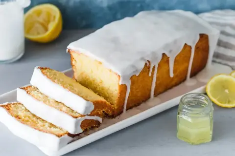 Saftiger Zitronenkuchen mit Zuckerguss, perfekt für ein einfaches zitronenkuchen rezept. Serviert mit frischen Zitronenscheiben.