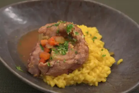 Ein köstliches Ossobuco-Rezept: zartes Kalbfleisch in Sauce mit Karotten und Sellerie, serviert auf cremigem Safranrisotto.
