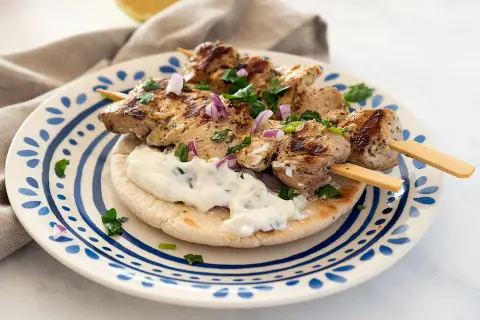 Saftige Hähnchen-Souvlaki-Spieße auf Pitabrot mit Tzatziki und roten Zwiebeln. Ein köstliches Souvlaki Rezept für den Sommer.
