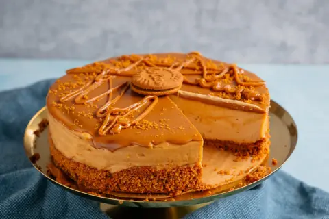 Ein köstlicher Lotus Kuchen mit Mascarpone, dekoriert mit Karamell und Kekskrümeln. Ein Stück fehlt bereits.
