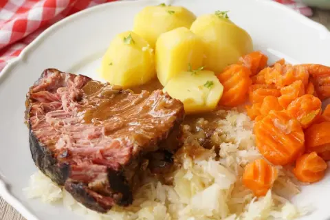 Saftiger Kassler im Ofen mit Salzkartoffeln, Möhren und Sauerkraut. Ein deftiges Gericht, das auf der Zunge zergeht.