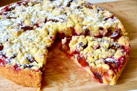 Saftiger Zwetschgenkuchen mit Hefeteig und Streuseln, frisch aus der Springform, mit Puderzucker bestäubt.