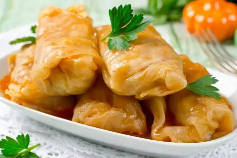 Kohlrouladen mit Hackfleisch in Sauce auf einem Teller, garniert mit Petersilie.