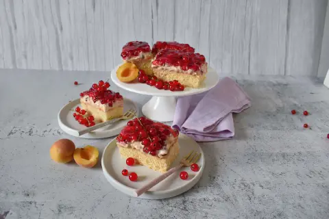 Saftiger Johannisbeerkuchen mit Quark und Pudding, garniert mit frischen roten Johannisbeeren und Aprikosen.