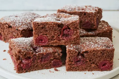 Saftiger Schokokuchen vom Blech mit Kirschen, bestäubt mit Puderzucker. Ein Genuss für jeden Schokoladenliebhaber.