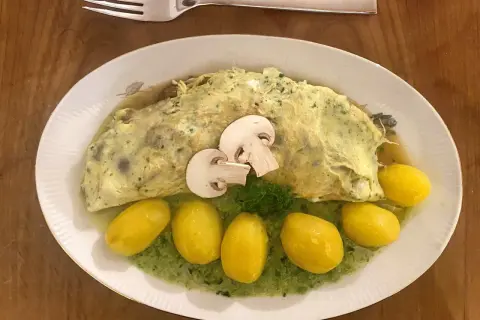 Ein Omelett mit Pilzen, serviert mit kleinen Kartoffeln und grüner Sauce. Perfekt für Pilz-Rezepte!