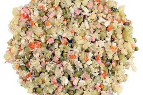 Ein Olivier Salat mit Kartoffeln, Erbsen, Karotten, Ei und Schinken. Perfekt für ein Picknick oder als Beilage.