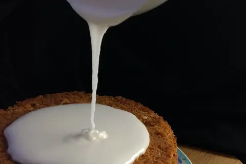 Zuckerguss Rezept: Ein Kuchen wird mit flüssigem Zuckerguss überzogen.