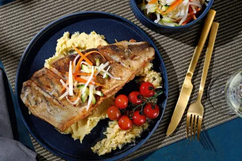 Gebratener Fisch auf Kartoffelpüree mit Kirschtomaten und knackigem Gemüse. Eine köstliche Beilage, die gut zu Kabeljau passt.