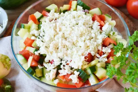 Frischer Schopska Salat mit Gurken, Tomaten und viel zerbröseltem Schafskäse, garniert mit Petersilie.