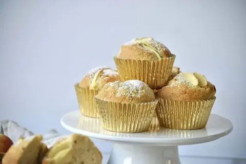 Goldene Apfelmuffins, bestäubt mit Puderzucker, warten auf das apfelmuffins rezept.
